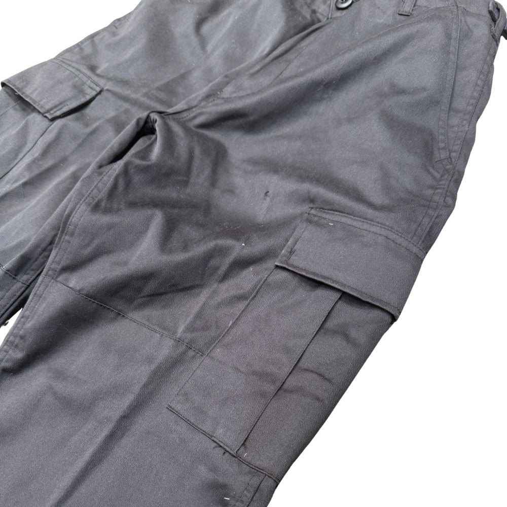 A close-up of black cargo pants showing the fabric texture, belt loops, and side cargo pockets against a plain white background.