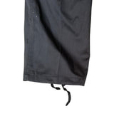 Close-up of a black fabric garment leg with a drawstring hem, shown against a plain white background.
